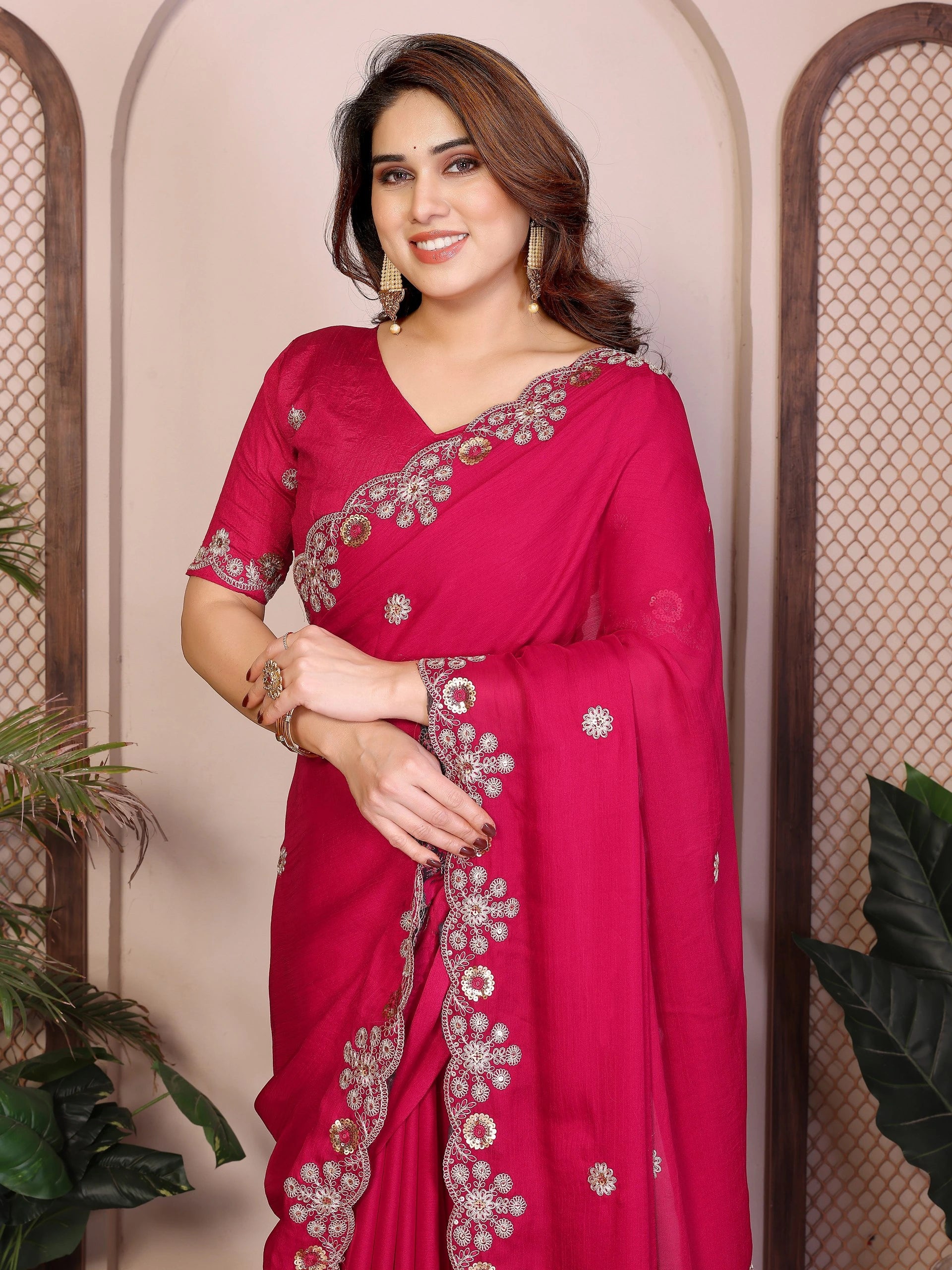 Woman wearing a pink saree with silver embroidery against a neutral background